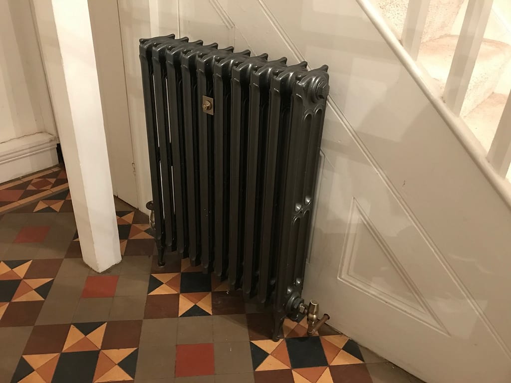 Arts and crafts hallway tiled floor with antique cast iron radiator