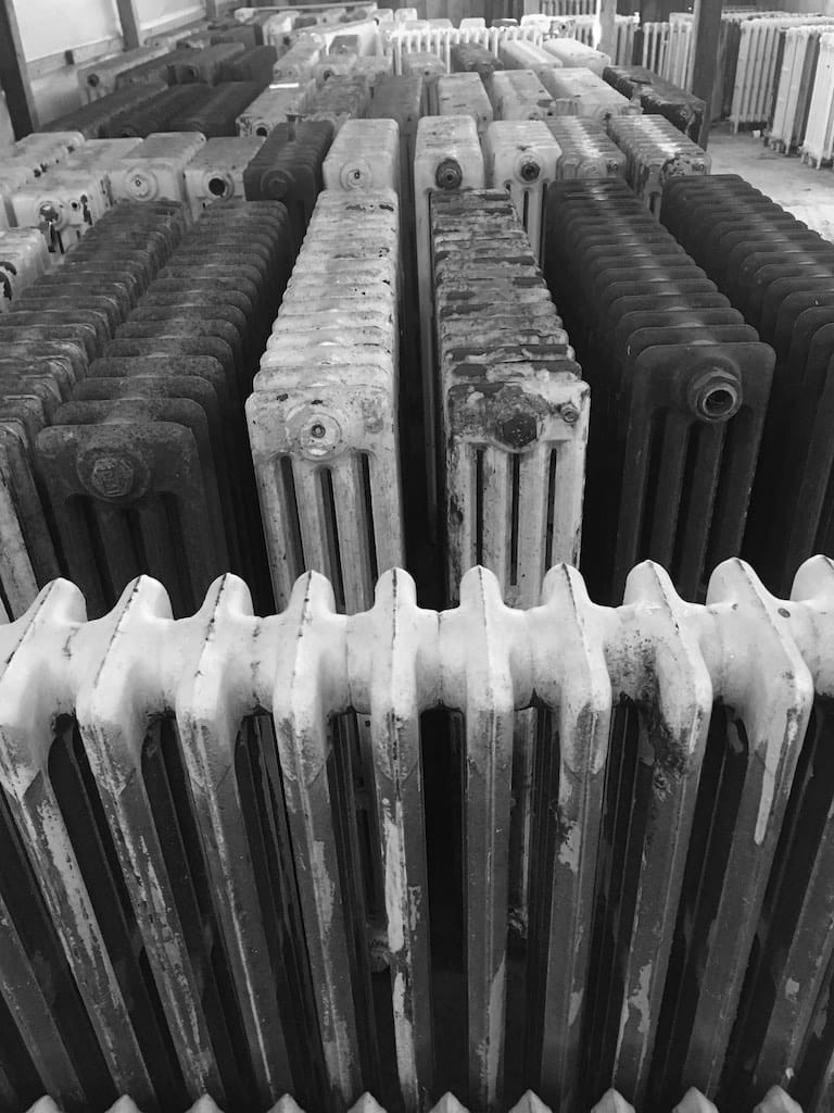 Large number of reclaimed cast iron radiators in warehouse